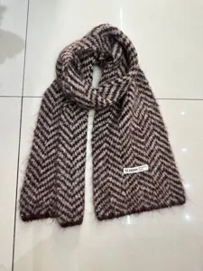 Primo piano di una sciarpa in maglia a motivo chevron marrone e bianco, morbida.