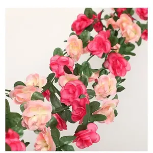 Artificial rose vine detail shot featuring pink and red silk flowers with green leaves for home.
