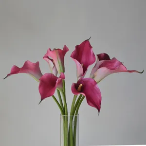 Gros plan de grandes fleurs artificielles Calla en EVA dans un beau vase en verre transparent.