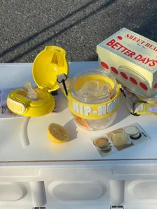 Close up of cute yellow plastic cup with hip-hop text and lemon slice outdoor scene