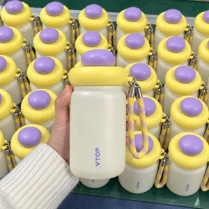 Detail view of a mini stainless steel thermos bottle with cute dome lid and portable braided cord.