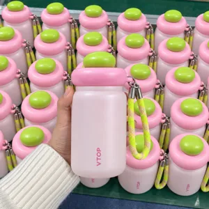 Portable mini thermal water cup, cute pink and green design with hand strap, detailed view.