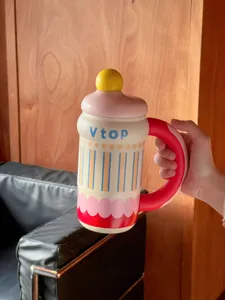 Novelty baby bottle shaped large capacity water mug with red handle and yellow top detail, detail shot.