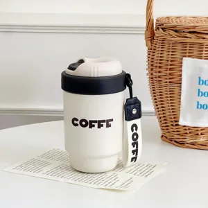 Close-up detail of a portable travel coffee mug with dual-drink lid and carrying strap.
