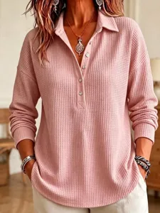 Detailed view of a casual pink waffle knit long sleeve top with lapel collar and button placket.