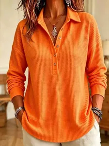 Orange waffle knit long sleeve polo top detail showing texture and button placket design.