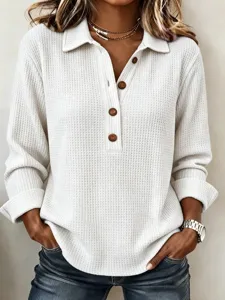 Detailed view of women's waffle knit long sleeve top with lapel and brown buttons.