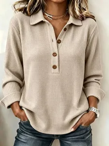 Closeup of the waffle knit fabric, lapel collar, and button details on the casual long sleeve top.