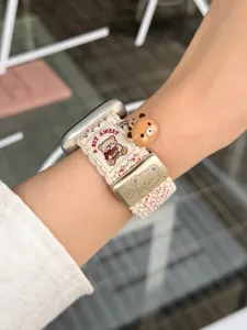 Nylon geweven horlogeband met schattige berenhanger en metalen gesp voor Apple Watch, beige.