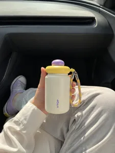 Close-up of cute mini insulated water bottle in car, portable pocket cup design with lanyard.