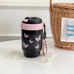Detail shot of a black mini thermal coffee cup with pink lid, cute butterfly print.