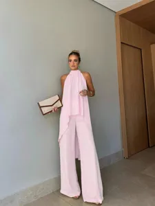 Detailed shot of the pink asymmetric sleeveless top and elegant wide-leg trousers outfit.
