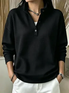 Close-up of black waffle knit long sleeve henley shirt showing button and fabric texture.