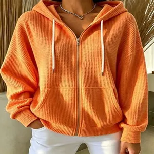 Orange waffle knit zip-up hooded sweatshirt, casual loose drop shoulder outerwear detail.