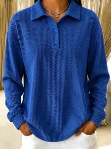 Detailed shot of a casual blue waffle knit polo shirt with button collar and long sleeves.