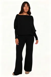 Close-up detail of the soft black knit off-shoulder top and flare pants set, smooth drape.