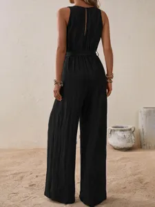Detailed back view of a stylish black sleeveless high-waist jumpsuit in a chic resort setting.