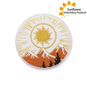 Round embroidered mountain and sun patch, detailed scenic fabric applique for clothing decor.
