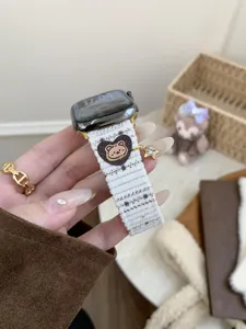 Close-up of cute corduroy watch strap with bear embroidery and gold star charm detail.