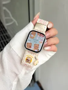 Detailopname van het geweven nylon Apple Watch horlogebandje met schattige berenhanger en metaal.