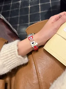 Nahaufnahme des niedlichen Welpen-Lederarmbands am Handgelenk, zeigt feine Designdetails.