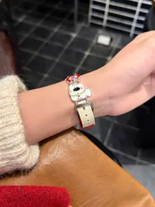 Nahaufnahme eines niedlichen Cartoon-Welpen-Armbands aus weißem Leder am Handgelenk.