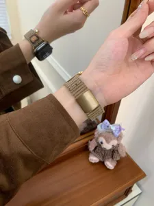 Detail view of brown corduroy apple watch strap with cute bear pattern and metal buckle.