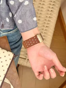Nahaufnahme eines braunen Nylon-Uhrarmbands mit weißen Sternmustern und Metallschließe.