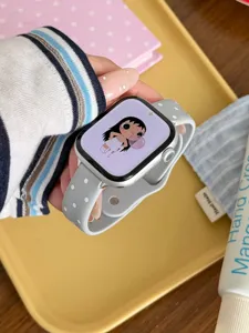 Primer plano de una correa de reloj de silicona gris con lunares blancos en la muñeca.