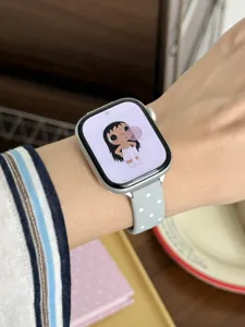 Detalle de la correa de reloj de silicona gris con lunares blancos llevada en la muñeca.