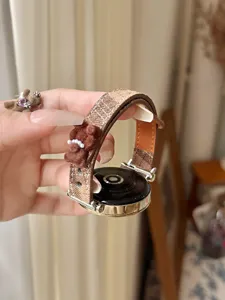 Detailed view of brown checkered smart watch band featuring a cute bear charm and connector.