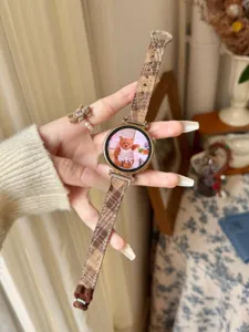 Plaid watch strap detail view, brown tartan fabric design with cute bear charm and buckle.