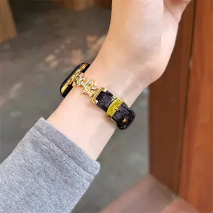 Gros plan du bracelet de montre en velours noir avec des étoiles en métal au poignet.
