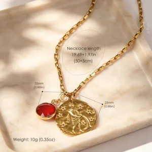 Gros plan détaillé du collier en chaîne dorée avec pendentif pierre rouge et médaille.