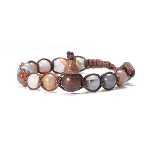 Gros plan sur le bracelet en pierre précieuse avec pendentif gourde en bois et cordon brun.