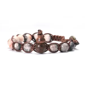 Gros plan détaillé d'un bracelet en perles de pierre naturelle avec pendentif hulu en bois.