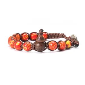 Gros plan détaillé du bracelet de perles en agate rouge et jaune avec une gourde en bois.