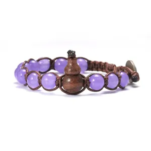 Vue détaillée du bracelet en perles violettes avec pendentif gourde en bois et cordon.