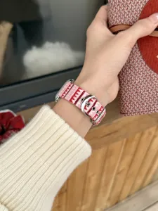 Detail view of the pink and red striped wave patterned Apple Watch replacement strap worn on wrist.