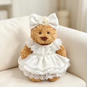 Süßer Plüsch Teddybär Puppe im eleganten weißen Satin Hochzeitskleid mit großer Schleife.