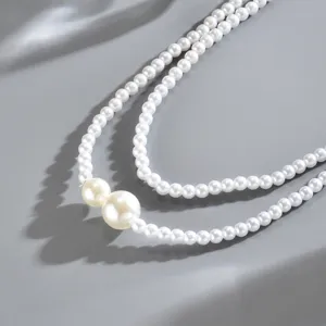 Vista dettagliata di una collana di perle bianche a doppio strato chic con grandi perle asimmetriche.