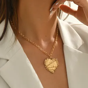 Close-up view of the textured gold heart pendant necklace, elegant collarbone jewelry.