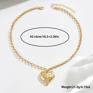 Gold hammered heart pendant detail view, delicate clavicle chain jewelry close-up shot.