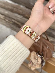 Close-up detail view of autumn winter woven watch strap compatible with apple watch with gold buckle