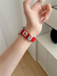 Detailed view of a red woven smartwatch replacement strap featuring a cute bear and sweet charm.