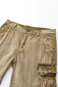 Detailed view of men's vintage brown cargo shorts with camo pocket and button closure.
