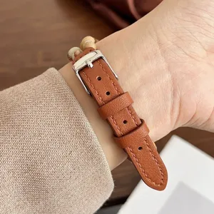 Primo piano del cinturino per orologio in pelle marrone con perle e fibbia in argento.