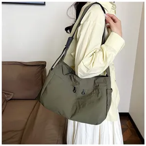 Detail shot of dark green nylon utility crossbody shoulder bag with large capacity and pockets.