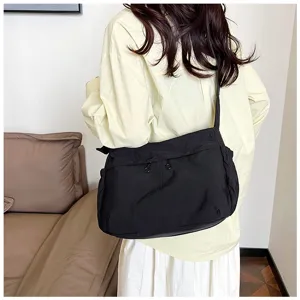 Detail shot of black nylon crossbody shoulder bag worn by model, casual utility style.