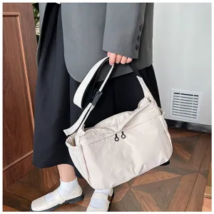 Detail shot of casual nylon shoulder crossbody bag in cream color with wide strap.